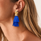 Brinco dourado com franjas azuis em camadas, detalhe na orelha