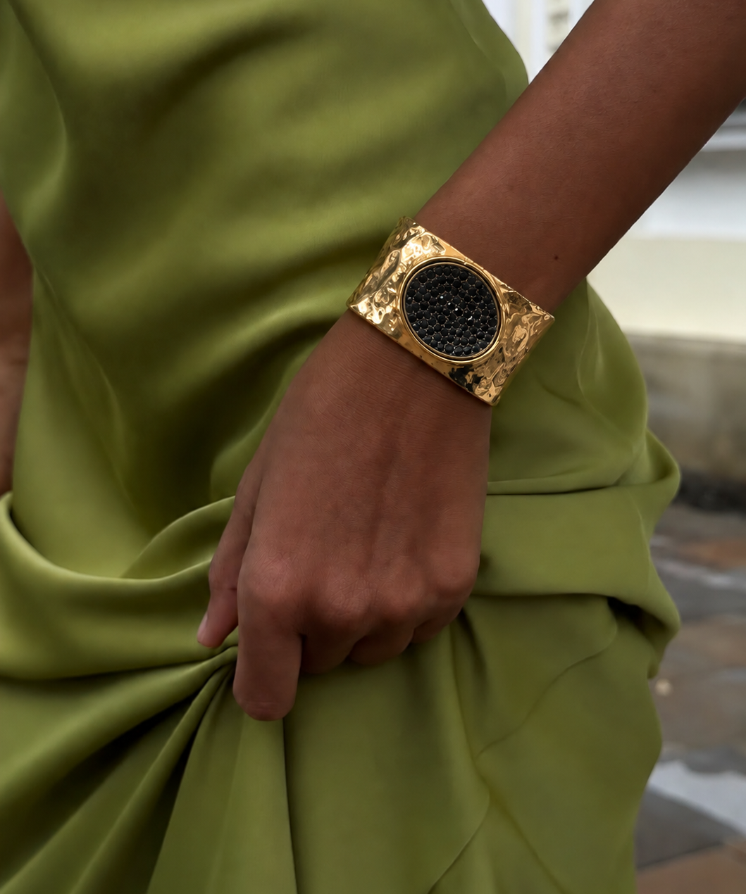 Bracelete largo dourado com base texturizada e pedra oval preta ao centro