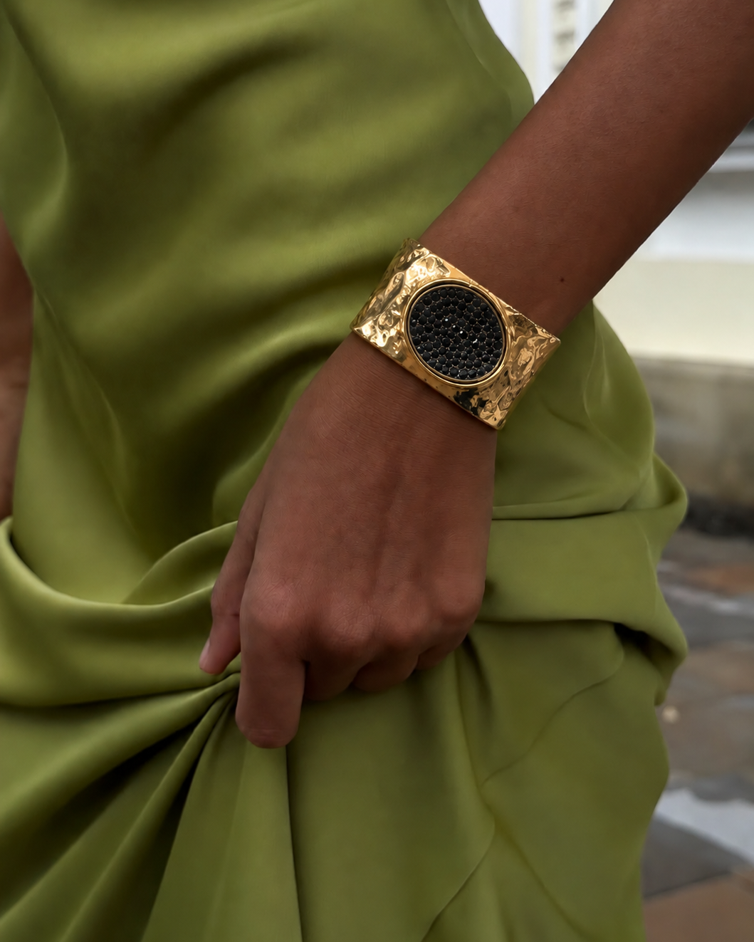Bracelete largo dourado com base texturizada e pedra oval preta ao centro