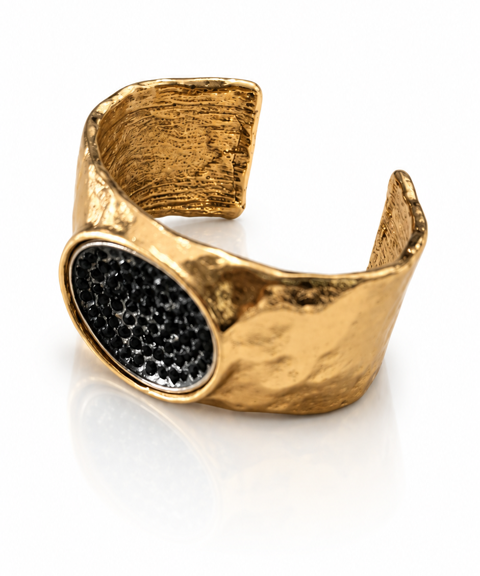 Bracelete dourado aberto com textura martelada e pedra oval preta em destaque