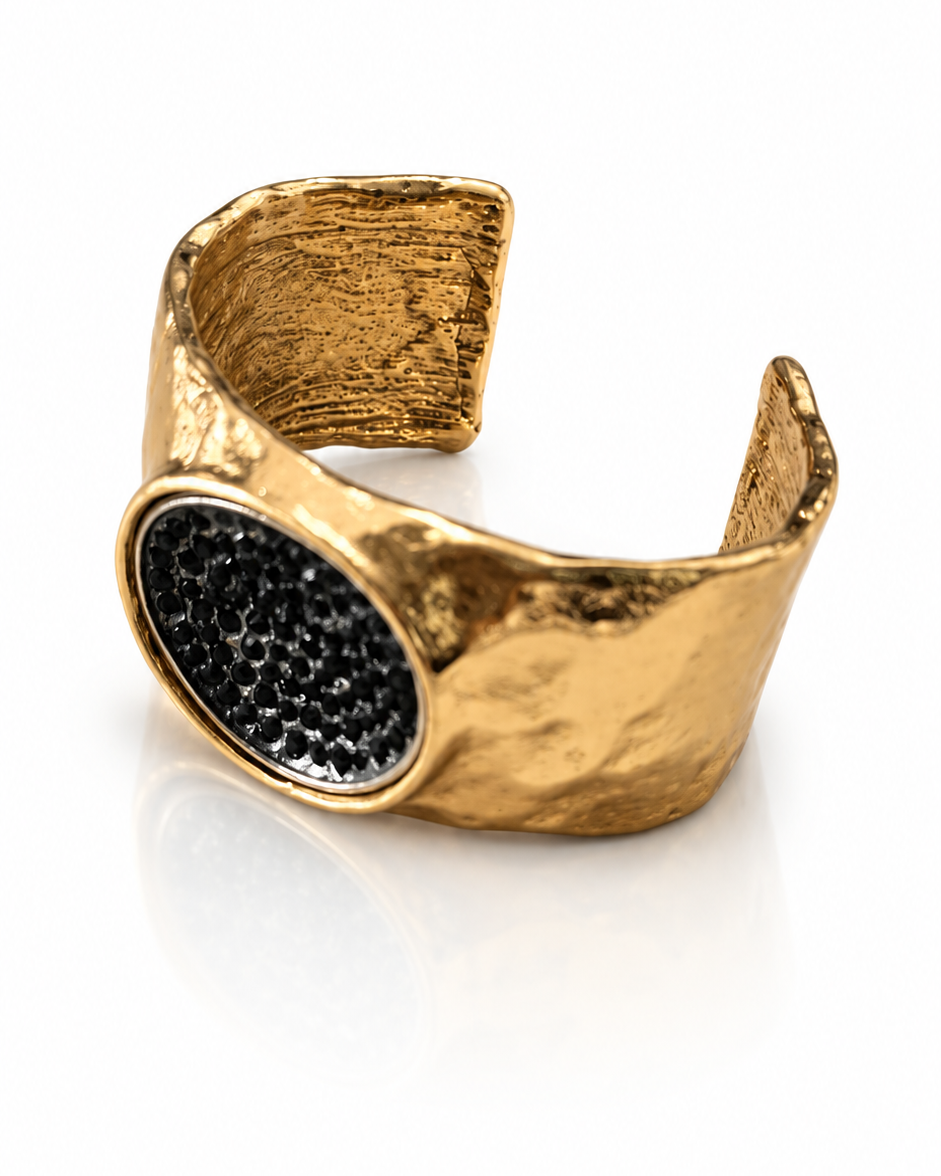 Bracelete dourado aberto com textura martelada e pedra oval preta em destaque