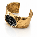 Bracelete dourado aberto com textura martelada e pedra oval preta em destaque