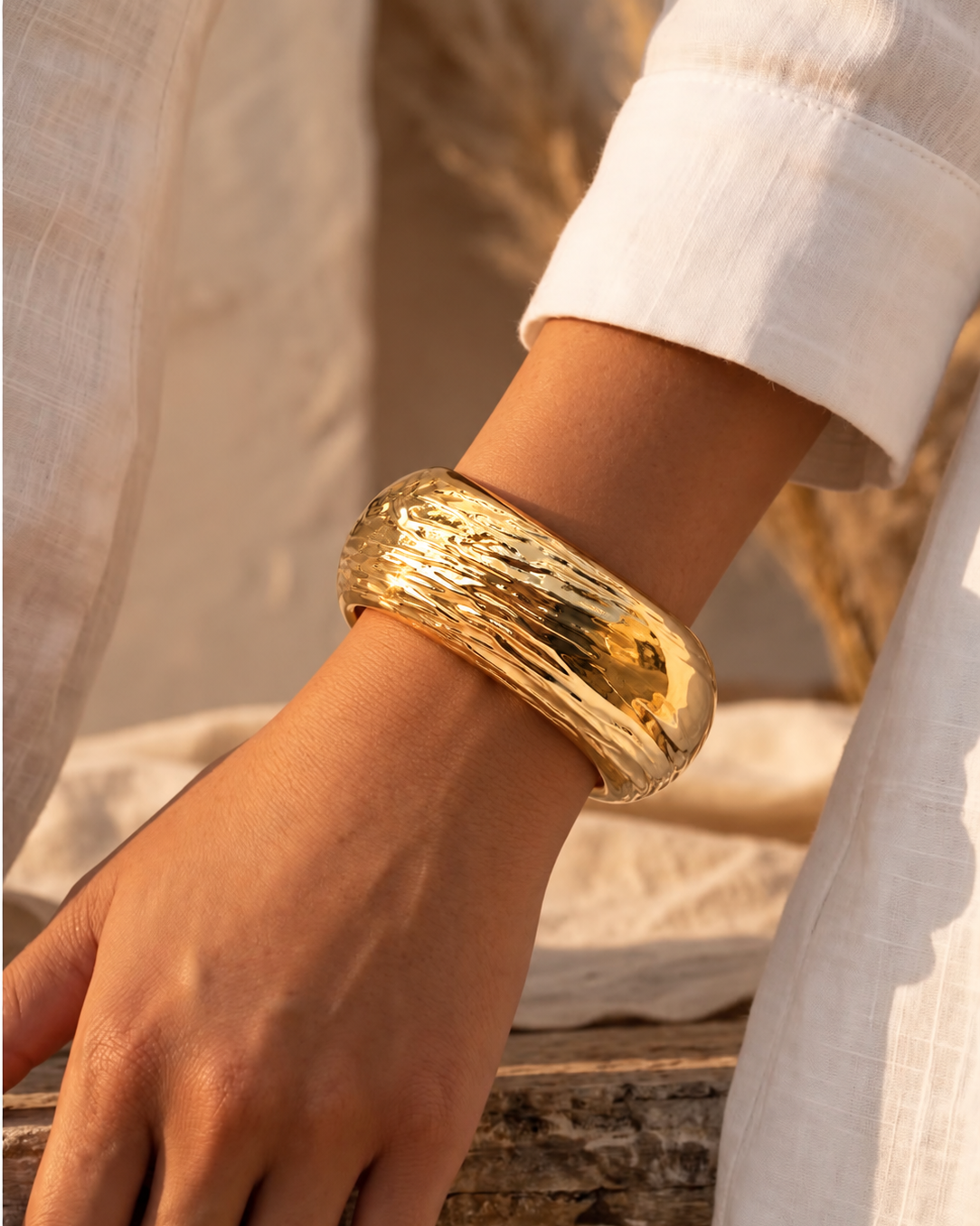 Pulseira bracelete dourada com textura ondulada no pulso