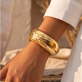 Pulseira bracelete dourada com textura ondulada no pulso