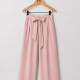 Calça rosa com laço na cintura e pernas amplas, com bolsos laterais