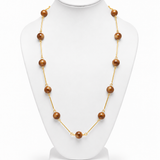 Colar longo de esferas caramelo com acabamento dourado e fecho discreto