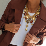 Colar dourado de corrente com pingentes coloridos, usado com blusa branca e blazer marrom