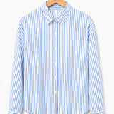 Camisa listrada vertical azul e branca, gola com botões frontais e punhos ajustados.