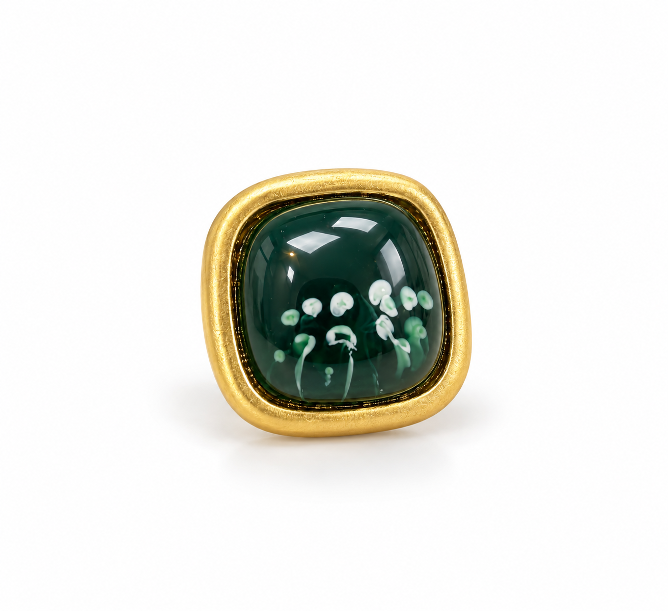 Anel dourado com pedra verde oval e detalhe floral branco na superfície