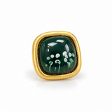 Anel dourado com pedra verde oval e detalhe floral branco na superfície