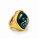 Anel dourado com pedra verde oval e borda grossa, vista lateral com detalhe floral