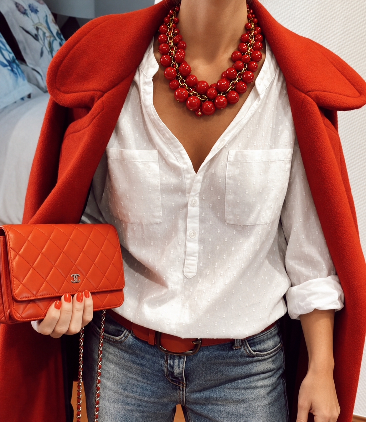 Colar vermelho de contas em camadas com detalhes dourados, usado no pescoço.