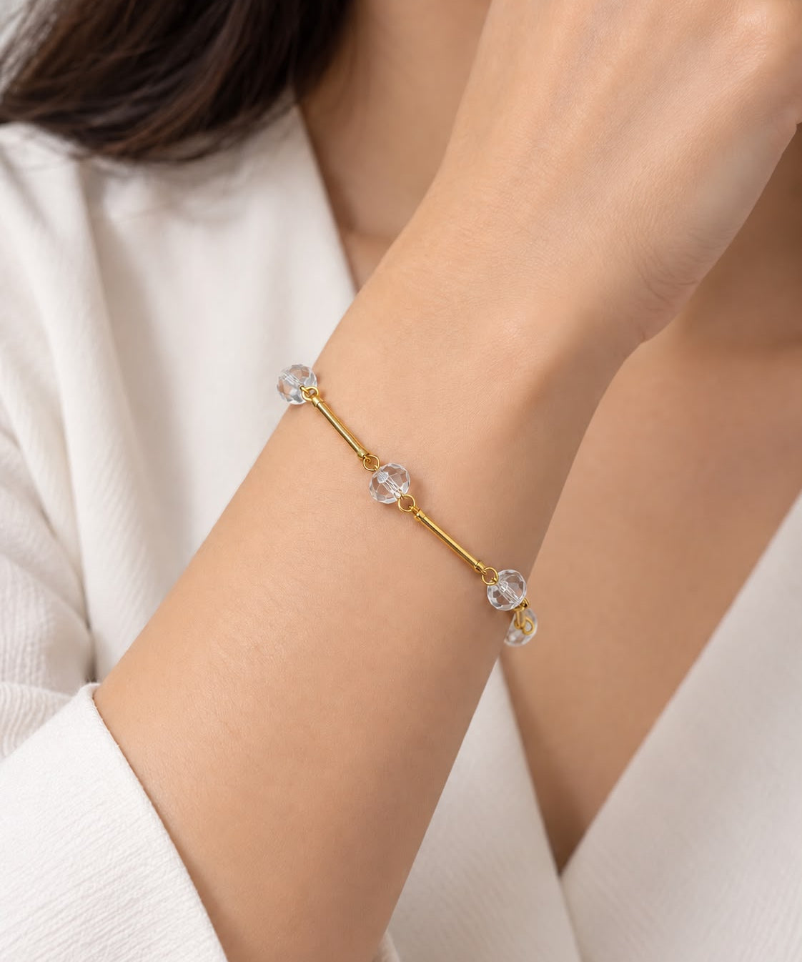 Pulseira dourada com cristais transparentes em formato oval e fecho elástico