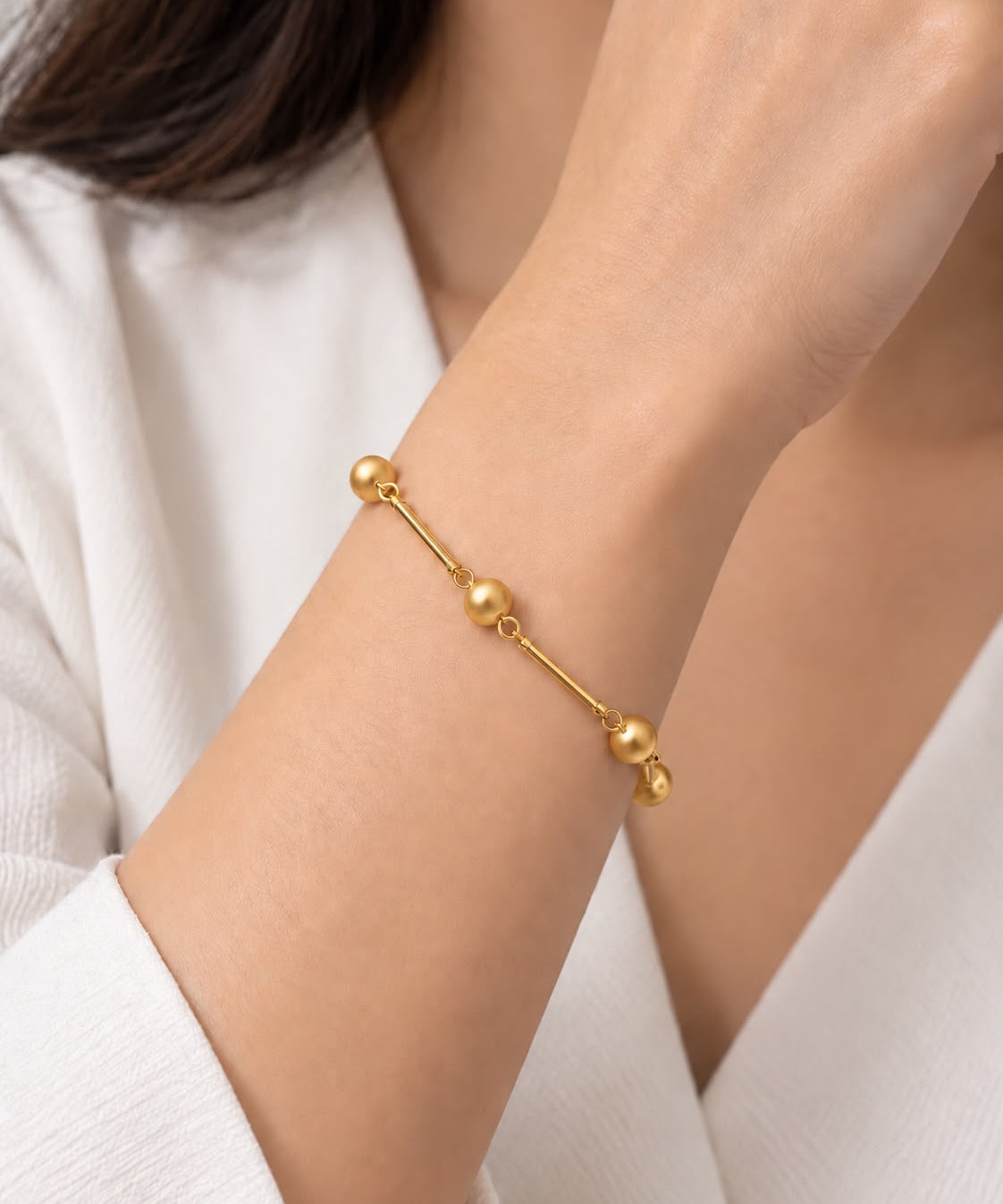 Pulseira dourada com elos e esferas redondas, ajustável no pulso