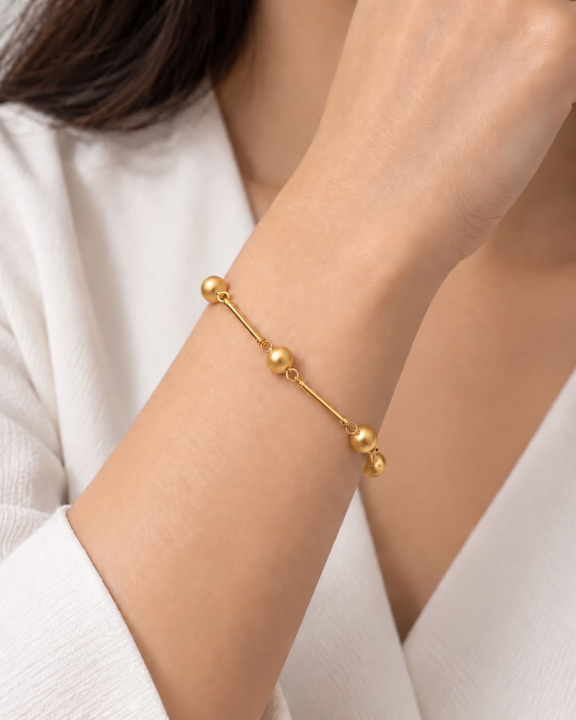 Pulseira dourada com elos e esferas redondas, ajustável no pulso