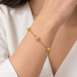 Pulseira dourada com elos e esferas redondas, ajustável no pulso