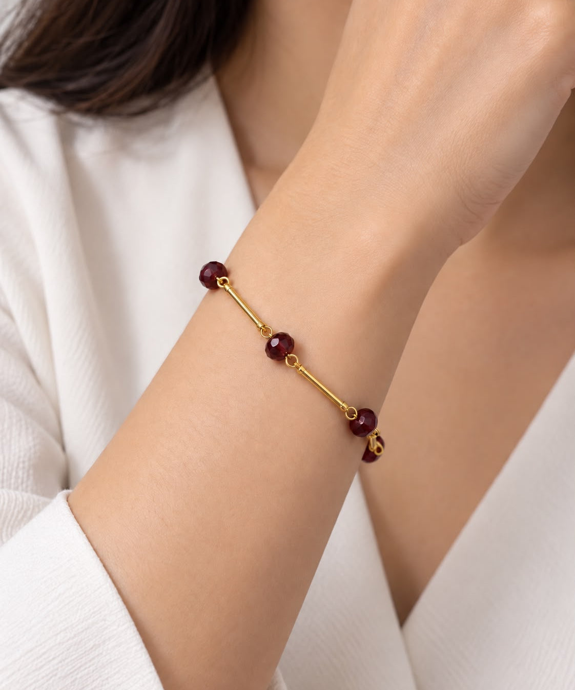 Pulseira dourada com esferas vinho e fecho discreto