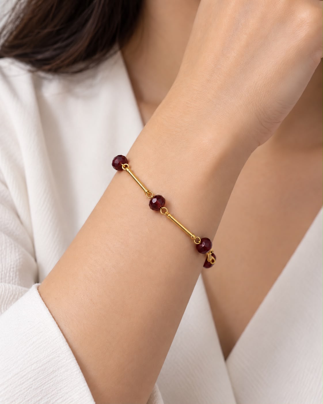 Pulseira dourada com esferas vinho e fecho discreto