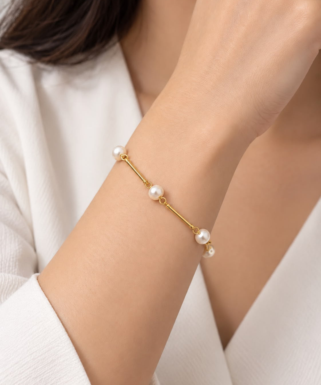 Pulseira dourada com pérolas esféricas e detalhes de argolas na corrente