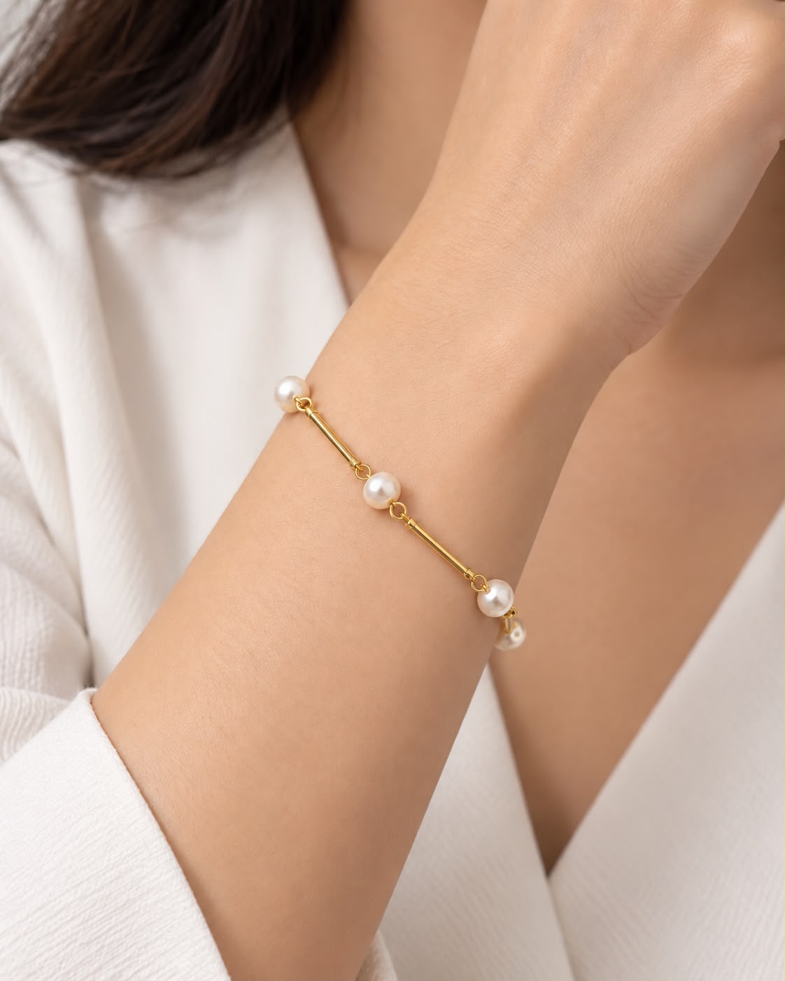 Pulseira dourada com pérolas esféricas e detalhes de argolas na corrente