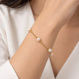 Pulseira dourada com pérolas esféricas e detalhes de argolas na corrente