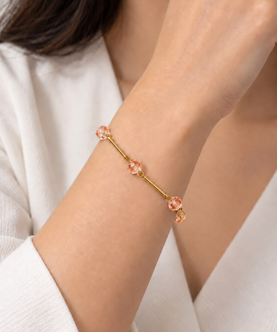 Pulseira dourada com pingentes pêssego e elos delicados no pulso