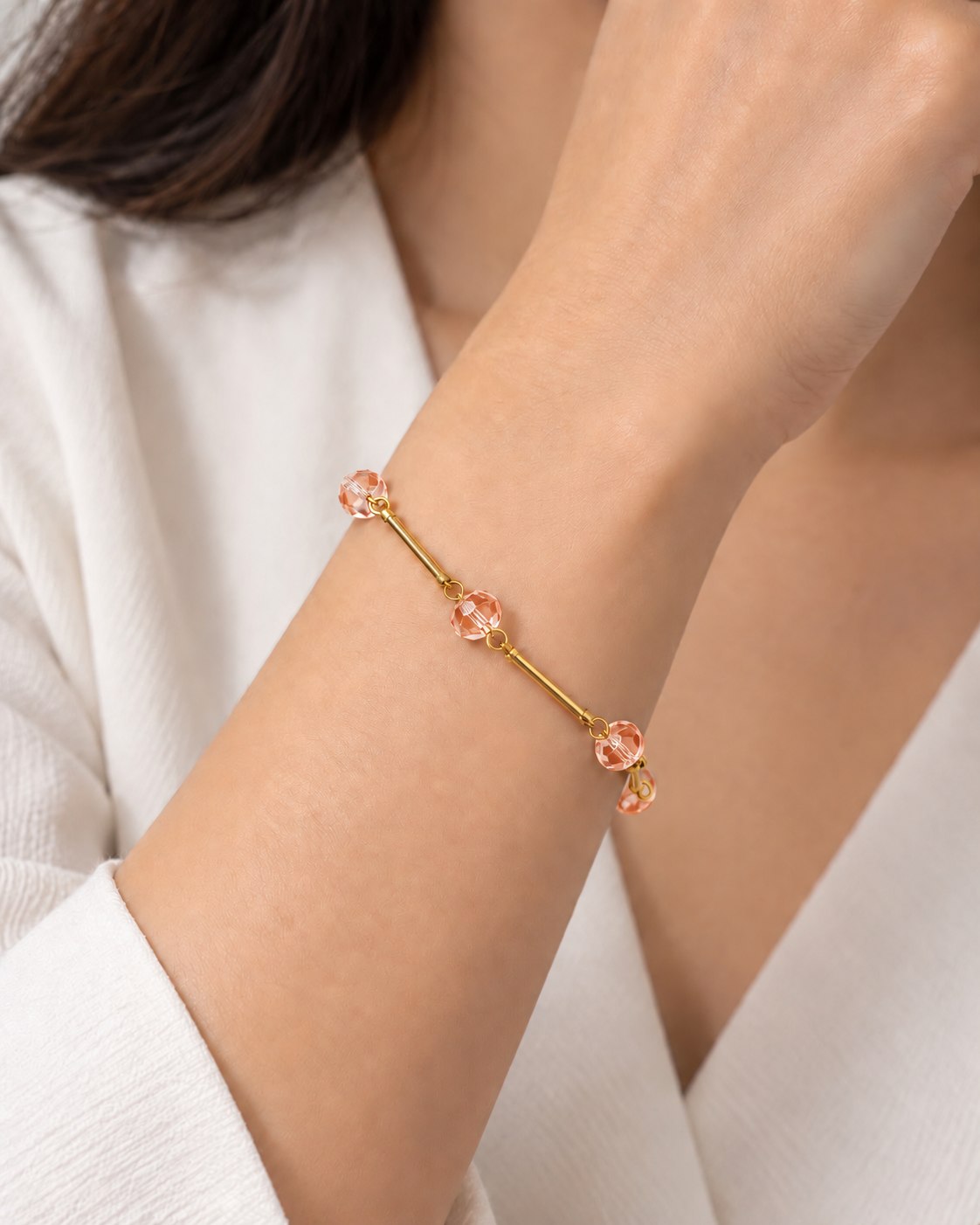 Pulseira dourada com pingentes pêssego e elos delicados no pulso