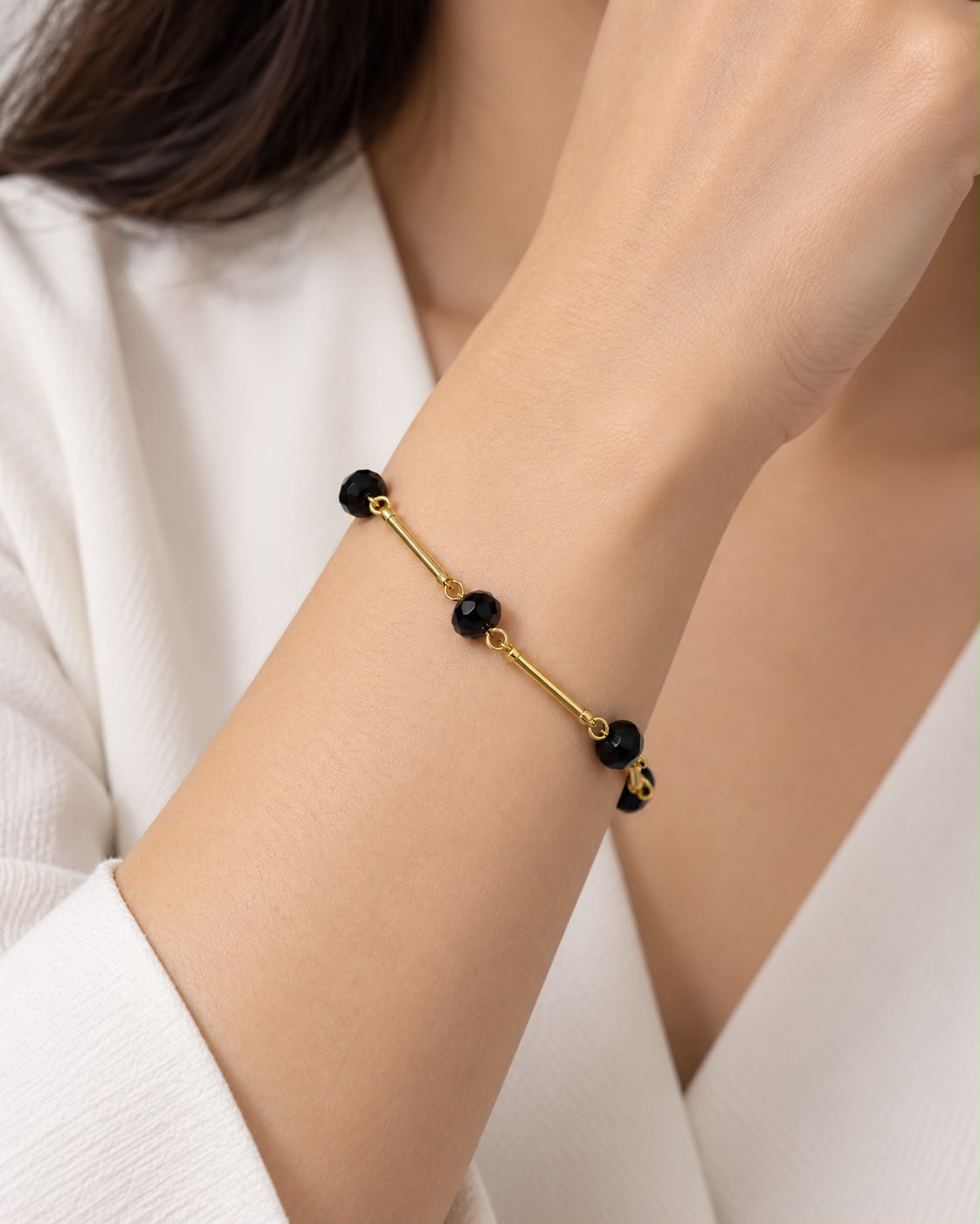 Pulseira preta com contas e fecho dourado, elos finos e detalhes arredondados
