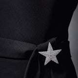 Broche de estrela com cristais prateados, preso ao tecido escuro.