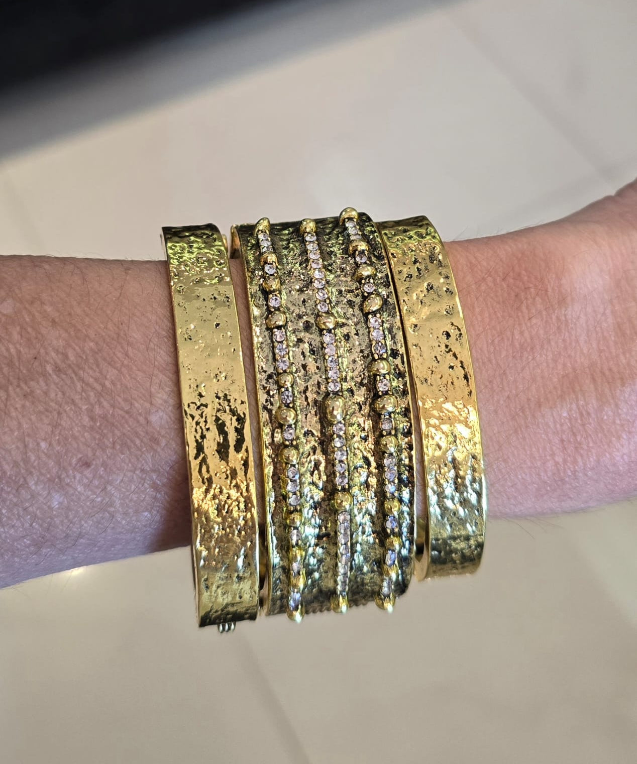 Pulseira mix com braceletes dourados e faixas de pedras brilhantes