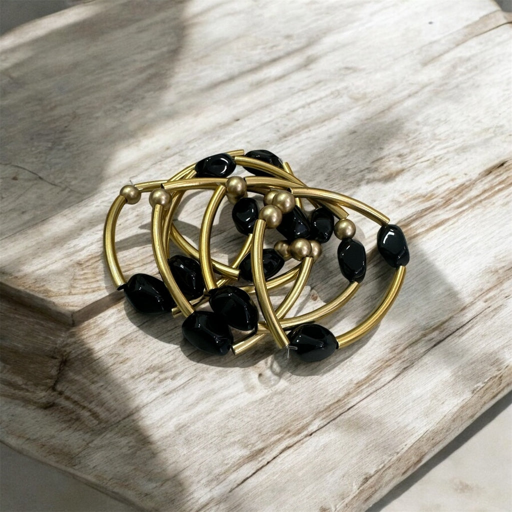 Pulseira de argolas douradas com contas pretas e esferas prateadas