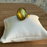 Anel oval dourado brilhante com pedra verde e aro dourado.