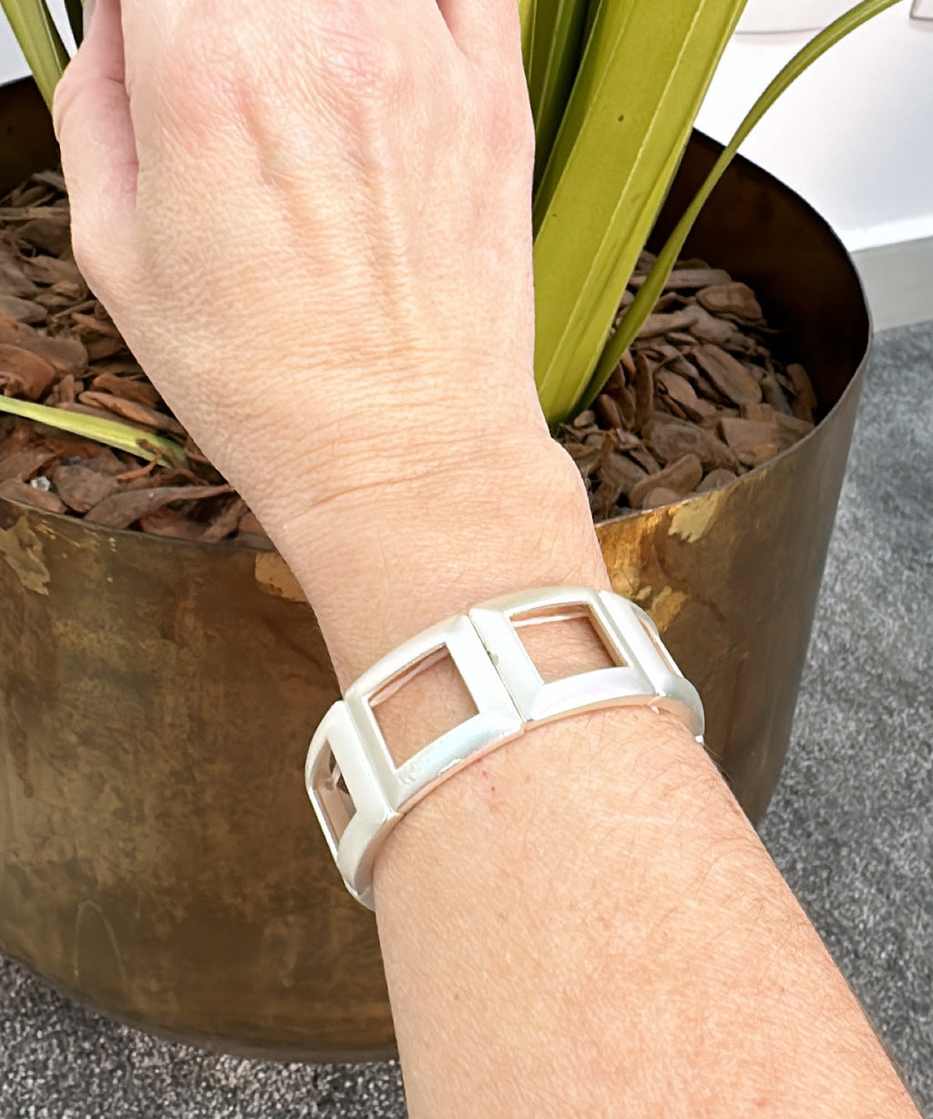 Pulseira dourada larga com inserções quadradas brancas no aro