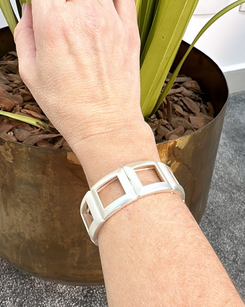 Pulseira dourada larga com inserções quadradas brancas no aro