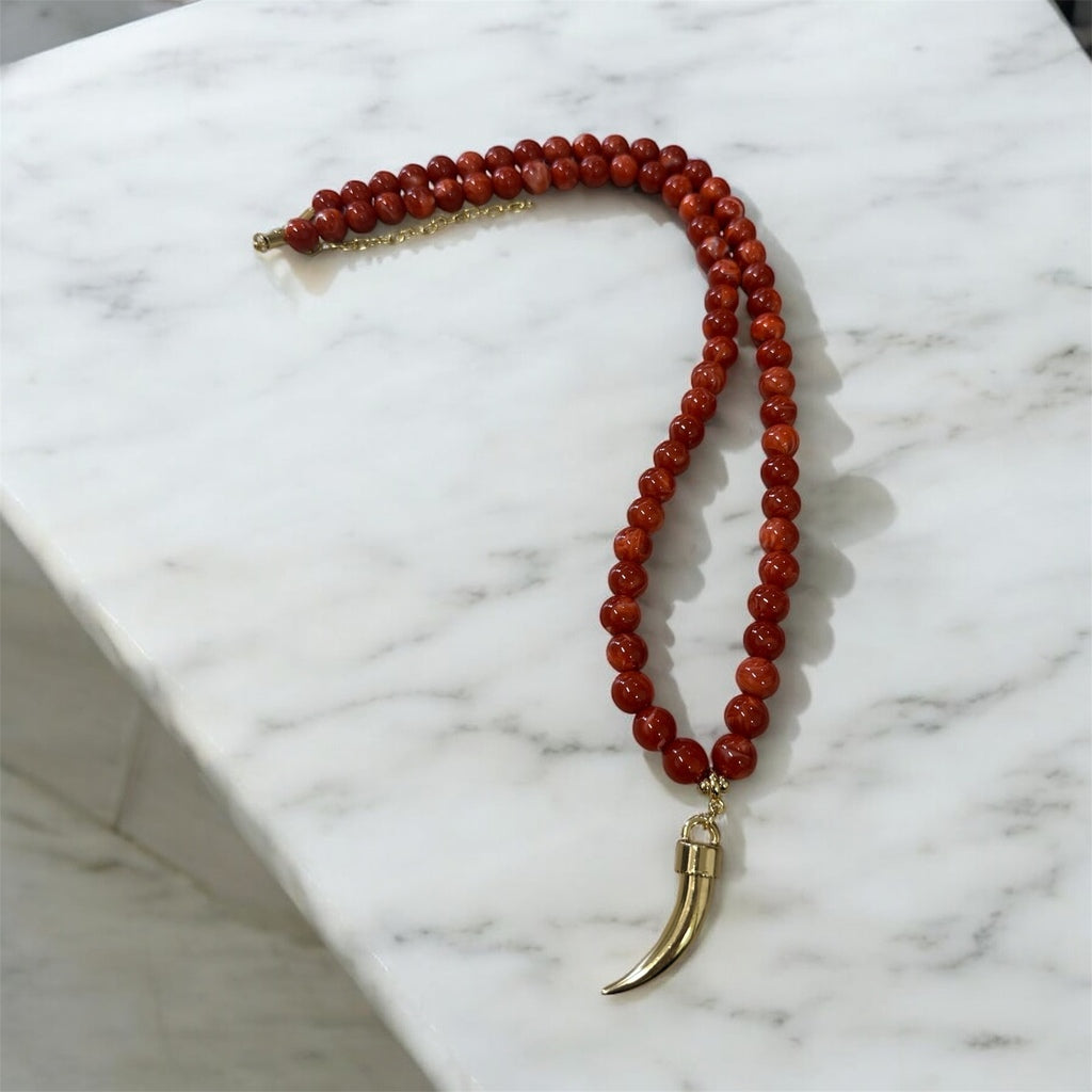 Colar de contas vermelho com pingente de chifre dourado e fecho metálico