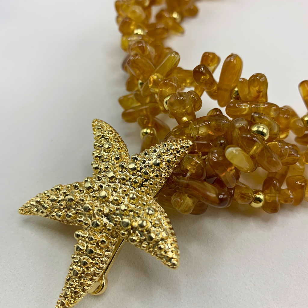 Colar de contas âmbar com estrela dourada grande e acabamento brilhante.