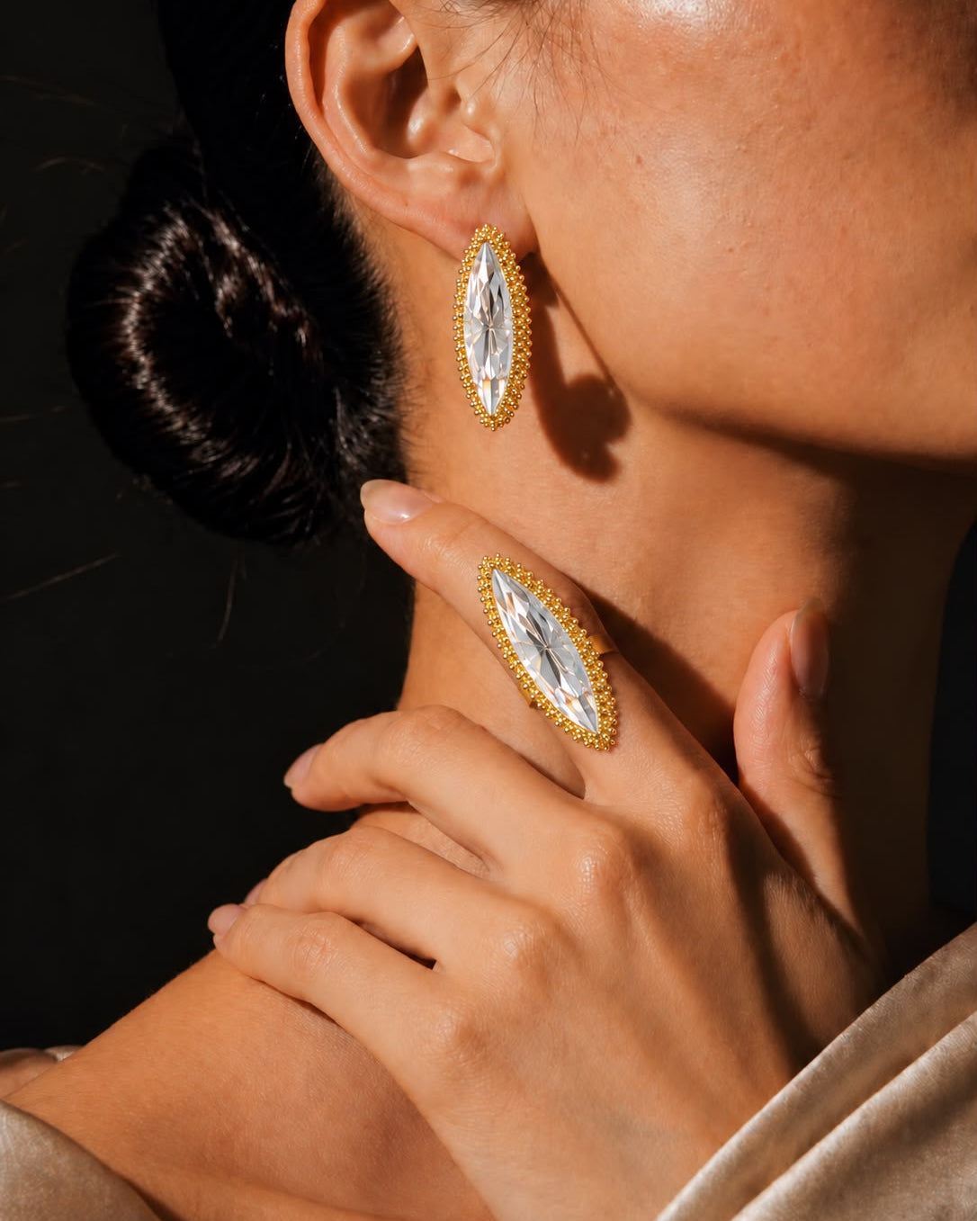 Anel Canoa com pedra cristal alongada e aro dourado, usado no dedo