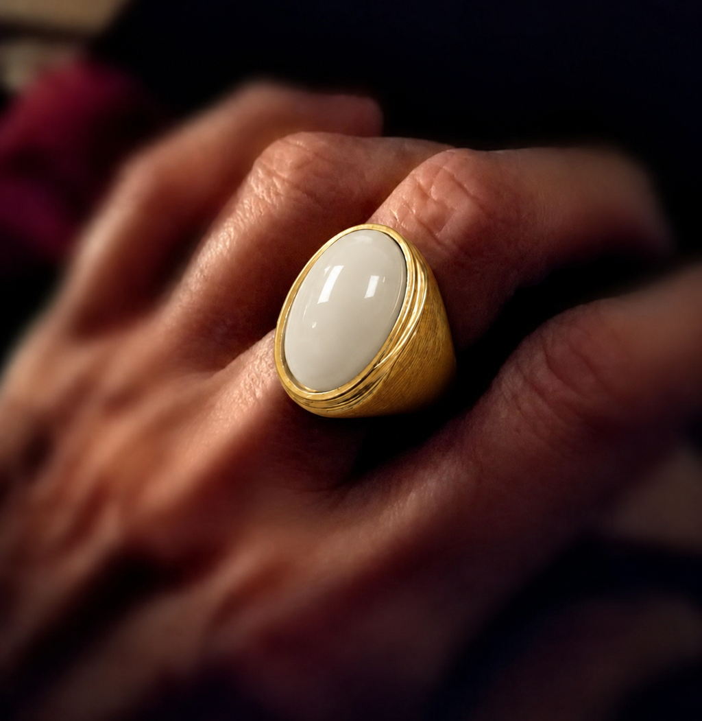 Anel dourado com pedra oval off-white brilhante e borda dourada