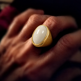 Anel dourado com pedra oval off-white brilhante e borda dourada