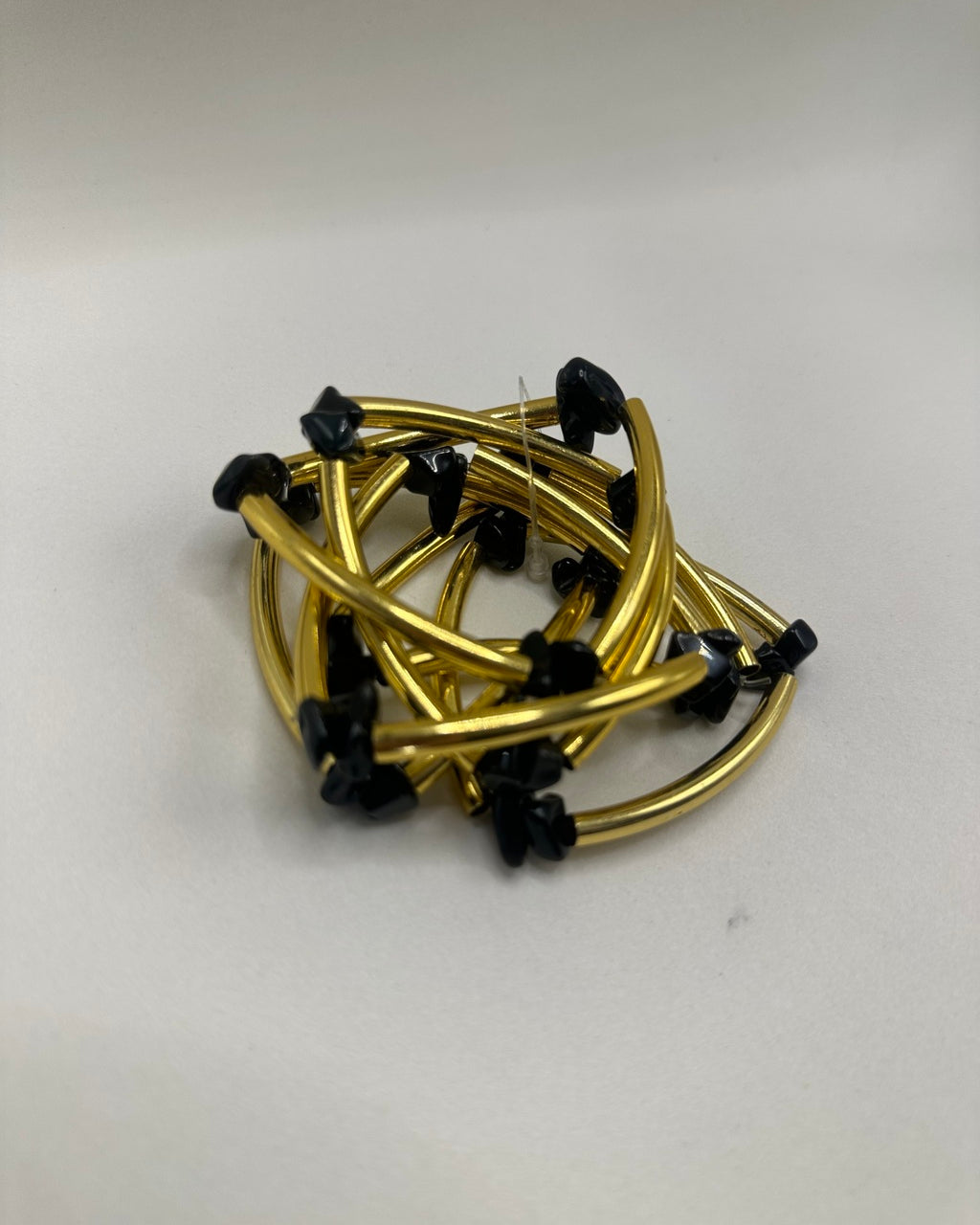 Pulseira folheada dourada com pedras pretas pequenas e elos curvos