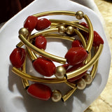 Pulseira de argolas douradas com contas vermelhas e esferas douradas