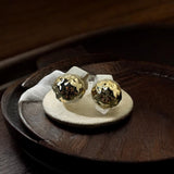 Par de brincos de metal dourado com esfera e padrão detalhado, formato de tarraxa