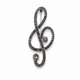 Broche em formato de clave de sol com detalhes de pedras brilhantes e pino