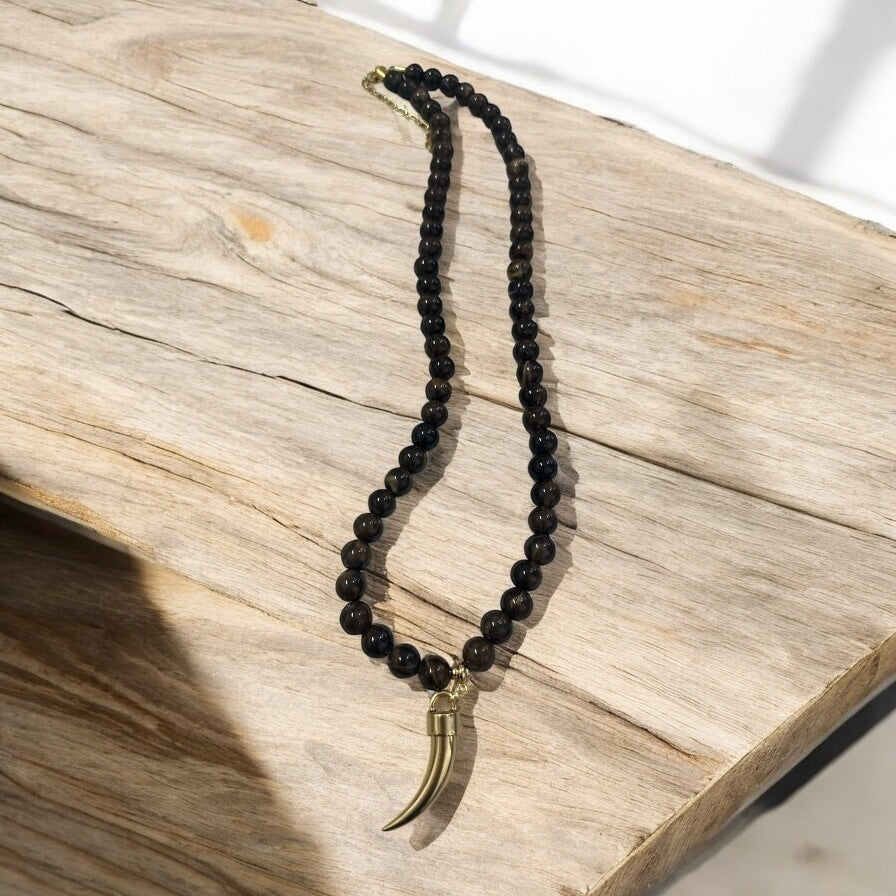 Colar de contas pretas com pingente de chifre dourado e fecho metálico