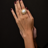 Anel Maiorca dourado com pérola branca; anel na mão com esmalte escuro