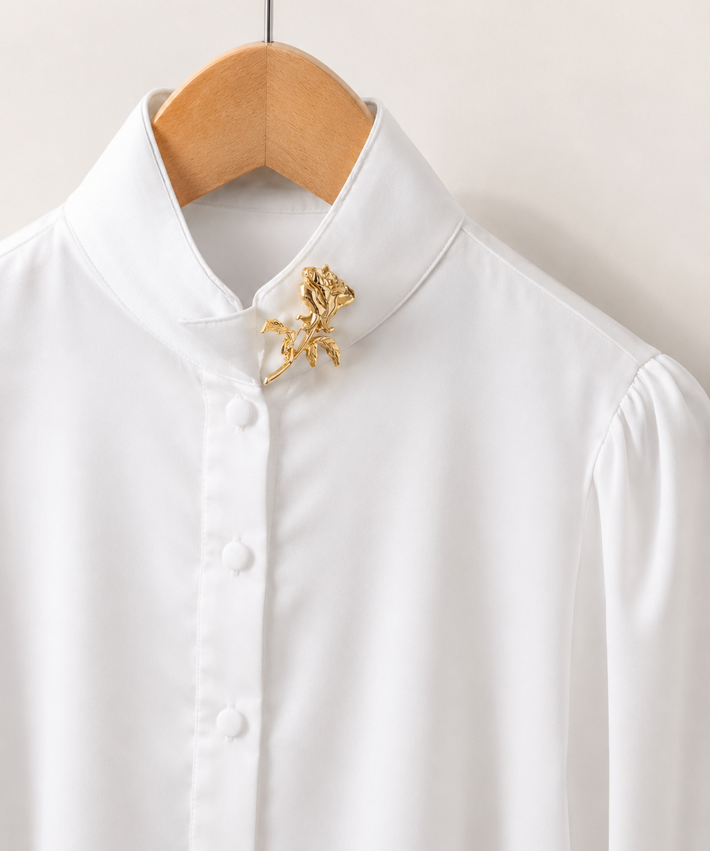 Broche de rosa em metal dourado preso à gola de camisa branca