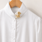 Broche de rosa em metal dourado preso à gola de camisa branca