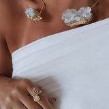 Anel Fabiana Gold dourado com pedra oval transparente, usado na mão