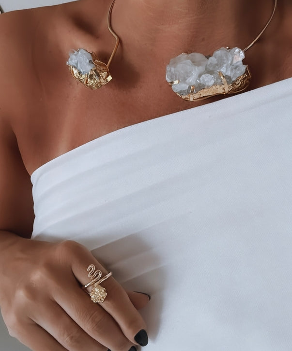 Anel Fabiana Gold dourado com pedra oval transparente, usado na mão