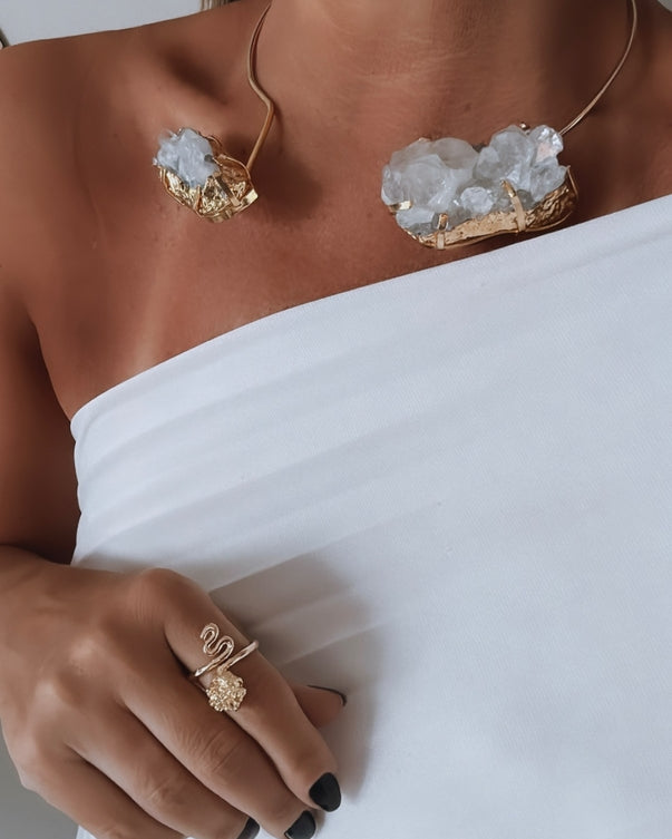 Anel Fabiana Gold dourado com pedra oval transparente, usado na mão